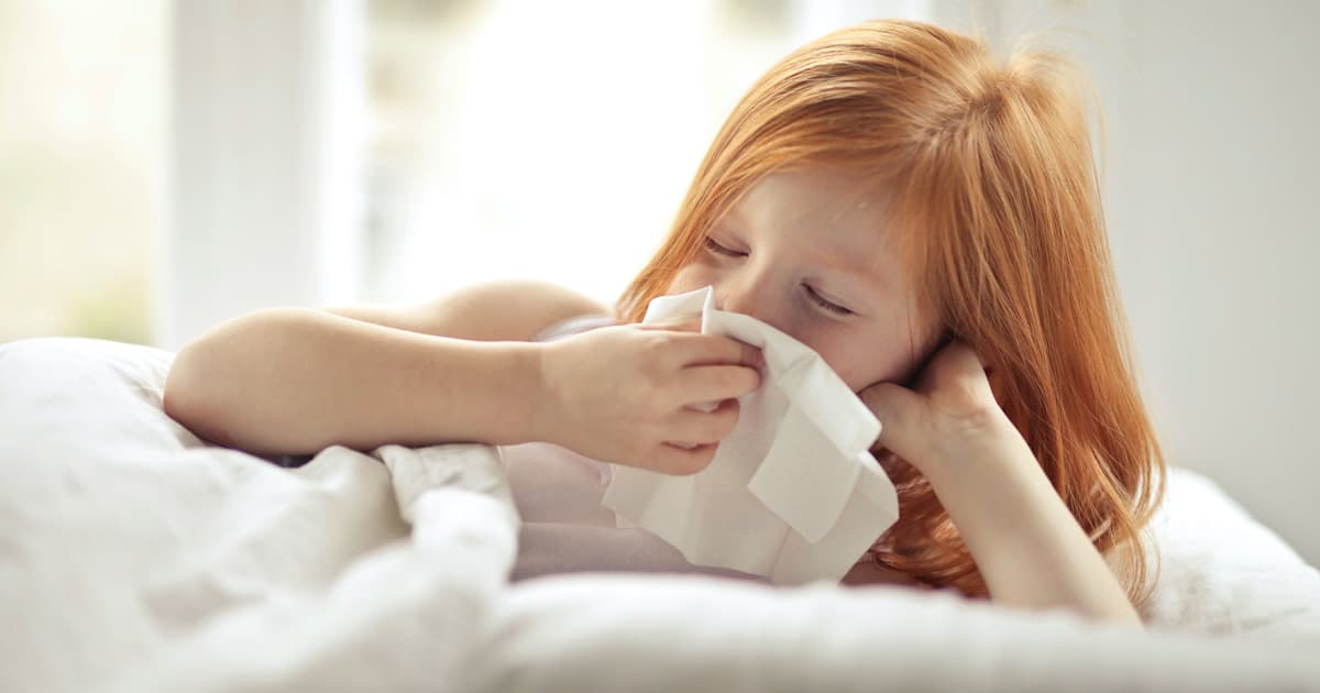 Sick child in bed, sneezing