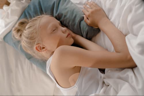 Blondes Mädchen schläft friedlich im Bett, unter ihrem Arm ist ein STEADYTEMP®-Patch zu sehen