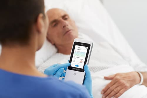 Krankenschwester liest mit der STEADYTEMP®-App die Temperatur von einem bettlägrigen Patienten aus